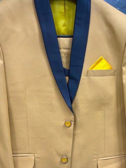 A men's formal blazer in tan with dark navy shawl lapels, featuring a matching yellow pocket square and yellow inner lining, displayed on a hanger.