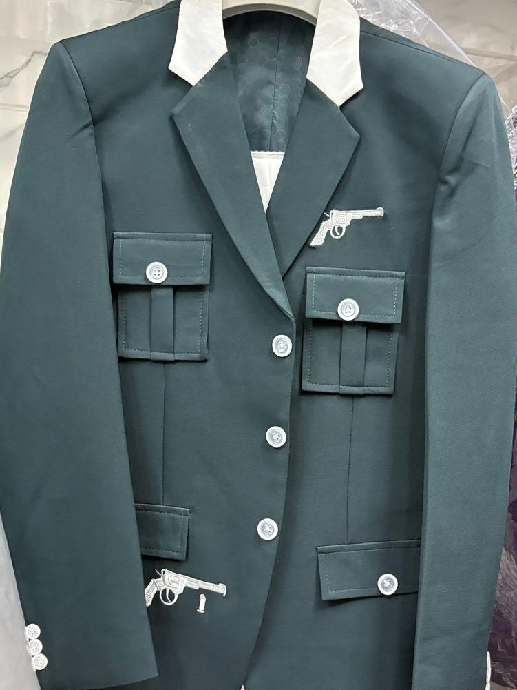 A dark green military-style blazer jacket with white buttons, a white pointed collar, and white pistol embroidery on the chest and cuffs, hanging on a hanger wrapped in protective plastic.