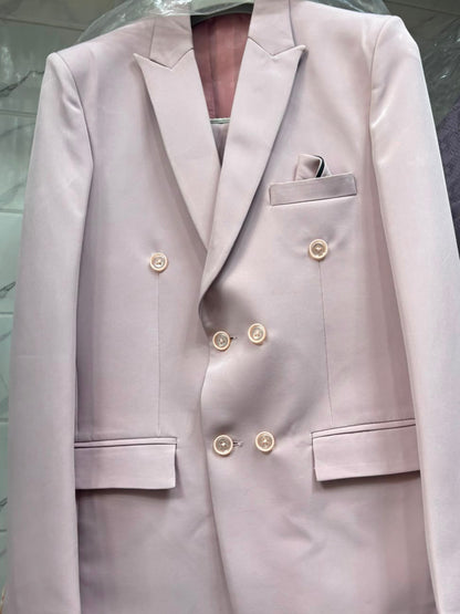 A light pink double-breasted blazer jacket with gold buttons, displayed on a hanger under a clear plastic cover.