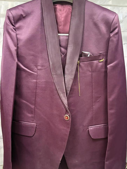 A men's single-breasted blazer in a rich plum purple satin-like fabric, featuring shawl lapels, a single button closure, flap pockets, and a matching pocket square, hanging on a white hanger.